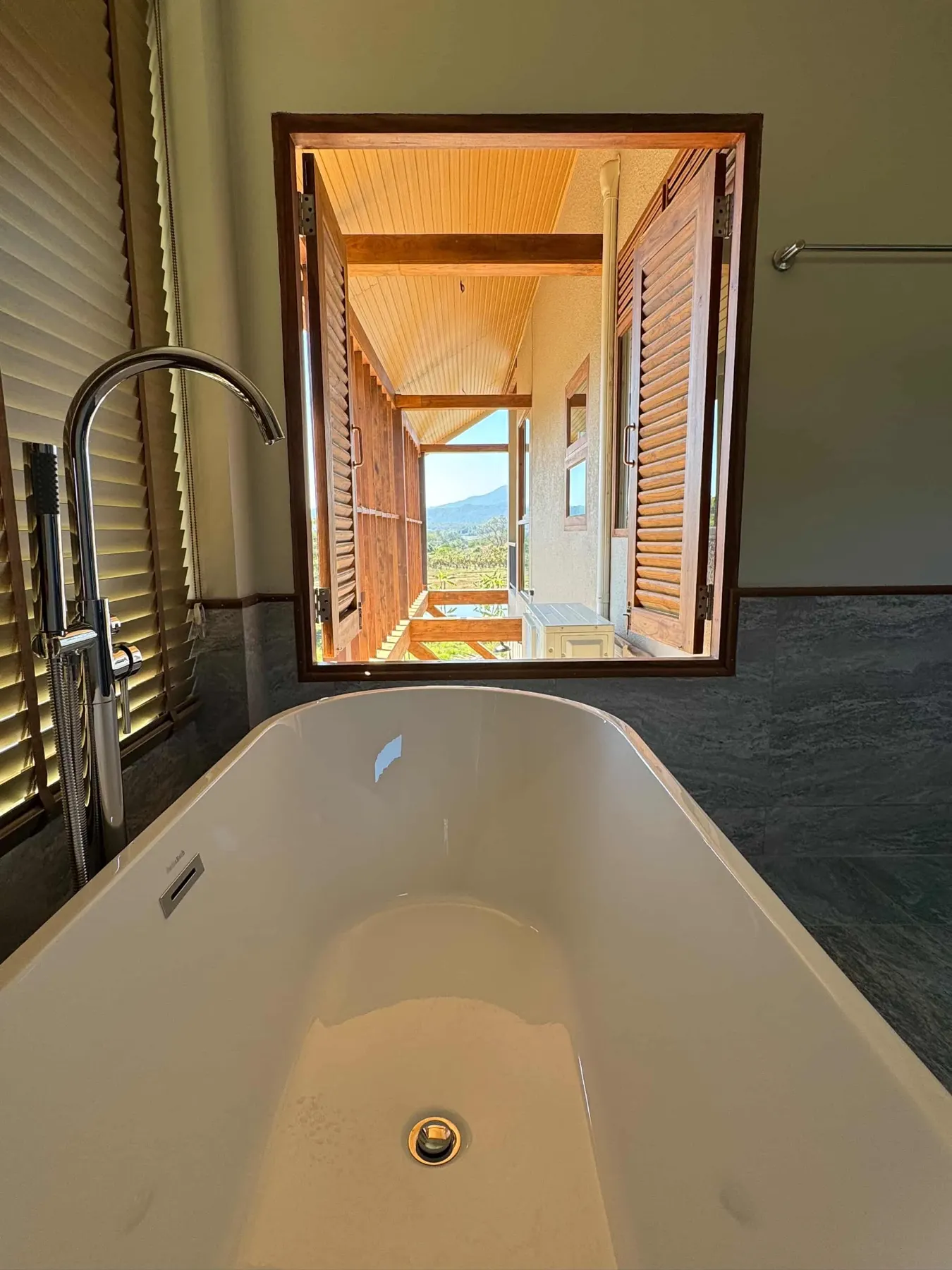Freestanding bathtub looking through to a wooden porch