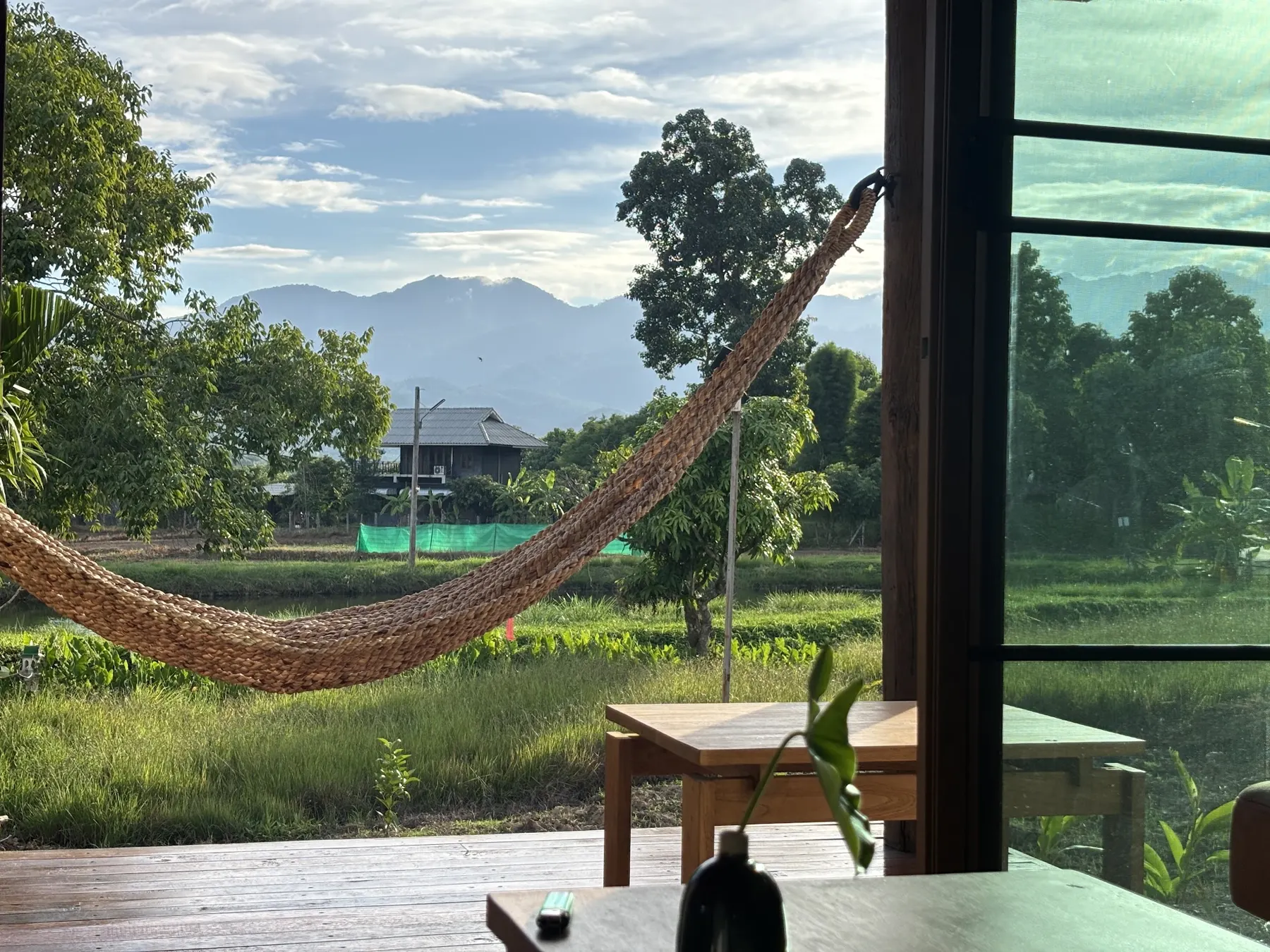 Rope hammock on the porch, with rice fields and mountains beyond